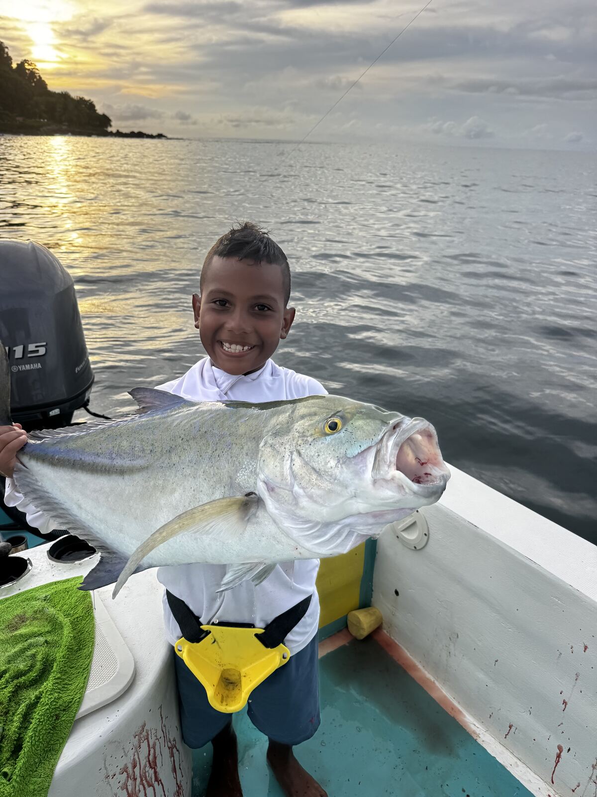 A boy smiling with his catch at sunset
